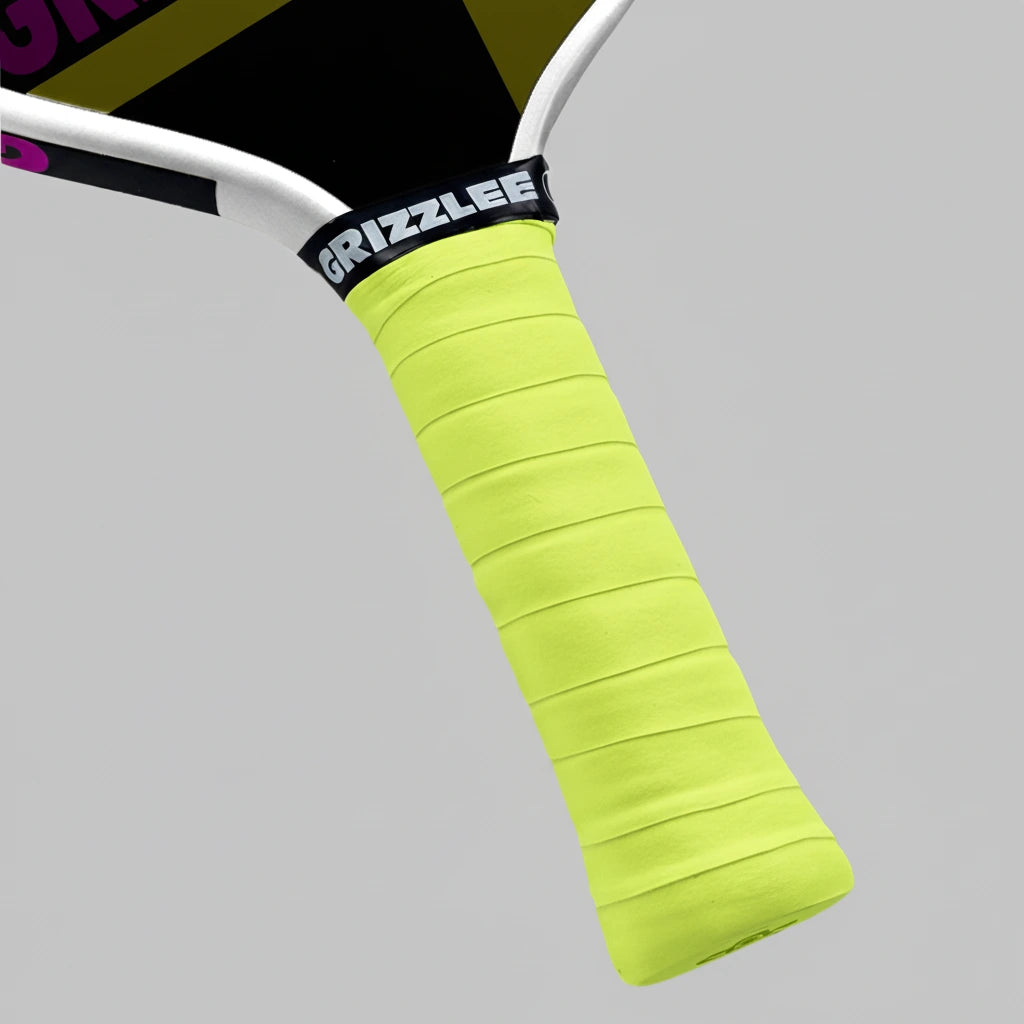 Close-up of a pickleball paddle overgrip with a bright yellow grip and 'Grizzlee Gripz' branding on a gray background.